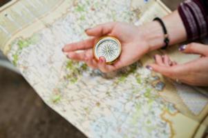 photo en gros plan de mains féminines avec boussole sur une carte.