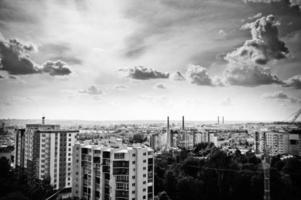photo en noir et blanc des toits avec vue sur la ville et du ciel nuageux.