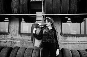 jeune fille hipster en veste jeans et foulard à la zone de montage des pneus. photo