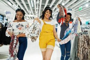 trois femmes africaines choisissant des vêtements au magasin. Jour de shopping. photo