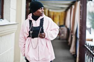 homme afro-américain de style urbain élégant en sweat à capuche rose posé. photo