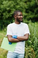 homme bénévole africain avec presse-papiers dans le parc. concept de volontariat, de charité, de personnes et d'écologie en afrique. photo