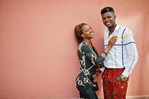 beau couple afro-américain élégant posé dans la rue ensemble amoureux contre le mur rose. photo