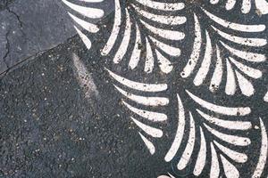 impression de feuilles blanches sur l'asphalte noir patiné, motif et texture, surface texturée patinée. photo