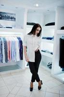 brune magnifique fille dans la boutique de vêtements décontractés, chemisier blanc et pantalon noir. photo