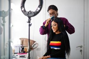 femme afro-américaine appliquant un coiffeur ou un coiffeur au salon de beauté. photo