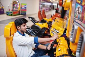 un mec asiatique s'affronte sur une machine de simulateur de course de jeu d'arcade speed rider. photo