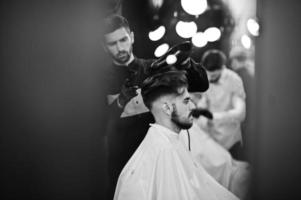 bel homme barbu au salon de coiffure, coiffeur au travail. photo