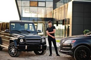 l'homme asiatique porte sur tout le noir posé près de la voiture suv. photo