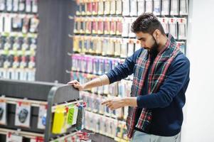 l'acheteur client de l'homme indien au magasin de téléphonie mobile choisit un étui pour son smartphone. concept de peuples et de technologies d'asie du sud. magasin de téléphonie mobile. photo