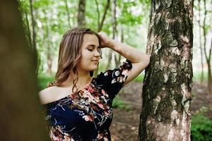 portrait d'une fabuleuse jeune fille en jolie robe avec une coiffure bouclée élégante posant dans la forêt ou le parc. photo