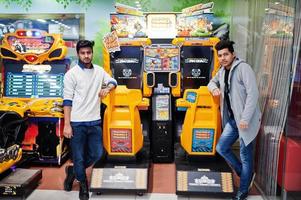 deux mecs asiatiques s'affrontent sur une machine de simulateur de course de jeu d'arcade speed rider. photo