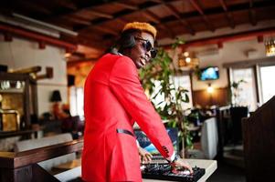 mode homme afro-américain modèle dj en costume rouge avec contrôleur dj. photo