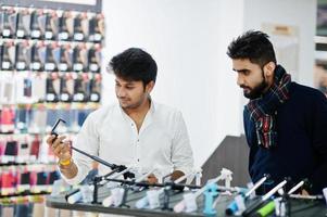 deux indiens mans client acheteur au magasin de téléphonie mobile choisissent un bâton de selfie. concept de peuples et de technologies d'asie du sud. magasin de téléphonie mobile. photo