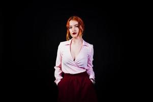 portrait d'une fille rousse en blouse rose et jupe marsala sur fond noir. photo