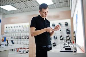 vendeur homme consultant professionnel en téléphonie mobile dans un magasin de technologie ou un magasin vérifier les nouvelles montres intelligentes. photo