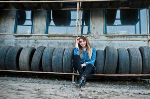 jeune fille hipster en veste jeans et foulard à la zone de montage des pneus. photo