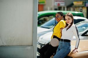 fille caucasienne blanche et afro-américaine noire ensemble contre une vieille voiture rétro. l'unité mondiale, l'amour racial, la compréhension dans la tolérance et la coopération dans la diversité des races. photo