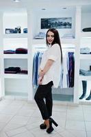 brune magnifique fille dans la boutique de vêtements décontractés, chemisier blanc et pantalon noir. photo