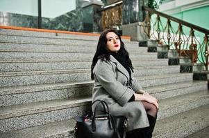 fille brune en manteau gris posé dans les escaliers de la gare à l'intérieur. photo