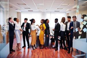 grand groupe de onze hommes d'affaires multiraciaux debout au bureau. groupe diversifié d'employés en tenue de soirée. photo