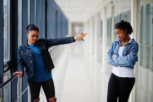 reste loin de moi. deux amies africaines en veste de jeans posées à l'intérieur ensemble. photo