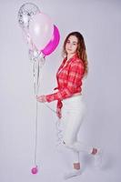 jeune fille en chemise à carreaux rouge et pantalon blanc avec des ballons sur fond blanc en studio. photo