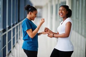 deux amies africaines en t-shirts jouent ensemble à l'intérieur avec des ciseaux à papier rock. photo