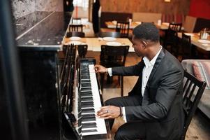 fort puissant homme afro-américain en costume noir jouer du piano. photo