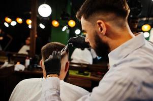 bel homme barbu au salon de coiffure, coiffeur au travail. photo