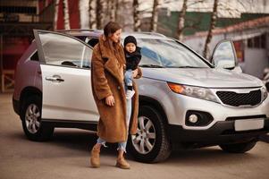 jeune mère et enfant se tiennent près de leur voiture suv. concept de conduite de sécurité. photo