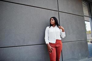 femme d'affaires afro-américaine formellement habillée en chemisier blanc et pantalon rouge. femme d'affaires prospère à la peau foncée. photo