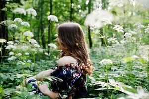 portrait d'une fabuleuse jeune fille en jolie robe avec une coiffure bouclée élégante posant dans la forêt ou le parc. photo