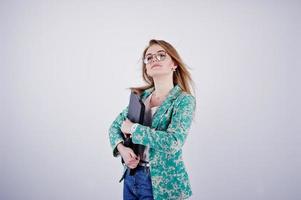 fille blonde élégante en veste et jeans à lunettes avec carnet de notes et ordinateur portable à mains sur fond blanc sur studio. photo