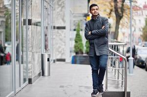 homme hindou indien élégant en manteau gris posé dans la rue. photo