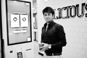 un client indien au magasin passe des commandes et paie via un kiosque d'auto-paiement pour la restauration rapide, un terminal de paiement. faire un choix de langue à l'écran. photo