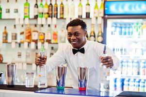 barman afro-américain travaillant derrière le bar à cocktails. préparation de boissons alcoolisées. photo