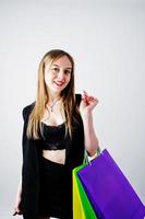 modèle de fille en vêtements noirs avec des sacs à provisions colorés posés au studio sur fond blanc. photo