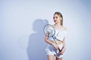 incroyable corps sexy brune caucasienne fille posant au studio sur fond blanc sur un short et un haut avec une raquette de badminton. photo