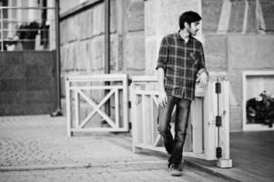 jeune étudiant indien en chemise à carreaux rouge et jeans posés à la ville. photo