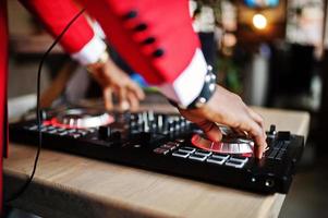 mains de la mode homme afro-américain modèle dj en costume rouge avec contrôleur dj. photo