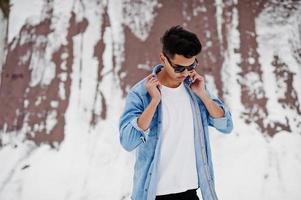 jeune homme indien décontracté en chemise de jeans bleu et lunettes de soleil posées le jour de l'hiver. photo