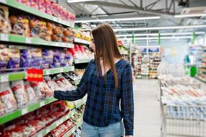 femme commerçante regardant les étagères du supermarché. portrait d'une jeune fille dans un magasin de marché. photo