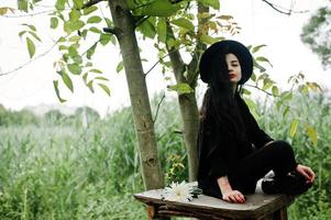 fille sensuelle tout en noir, lèvres rouges et chapeau. femme dramatique gothique. photo