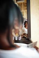 femmes afro-américaines élégantes en chemisier blanc et jeans bleus posés au café avec journal. photo