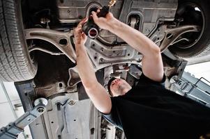 thème de la réparation et de l'entretien des voitures. mécanicien en uniforme travaillant dans le service automobile. photo