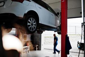 thème de la réparation et de l'entretien des voitures. mécanicien en uniforme travaillant dans le service automobile. photo