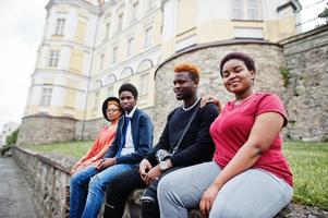 quatre amis africains s'amusant à l'extérieur. deux filles noires avec des gars sont assises dans une vieille ville. photo