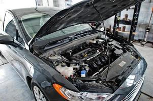 thème de la réparation et de l'entretien des voitures. moteur à capot ouvert de voiture en service automatique. photo