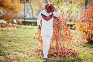 homme afro france élégant et branché en chapeau rouge et tenue blanche posée au jour de l'automne. gars modèle africain noir. photo